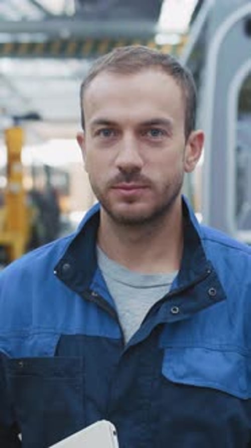 Professional Bearded Young Male Engineer Wearing Industrial Clothes Holding Tablet Computer Posing