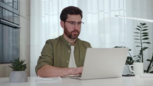 Man Working on Laptop at Home Desk