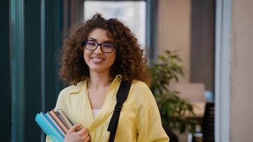 Smiling Young Woman with Books in Modern Office