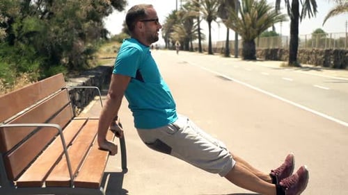Young Man Doing Push-Ups Using Bench in City Park, Super