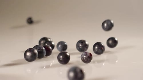 Blueberries poured onto a white surface in slow motion