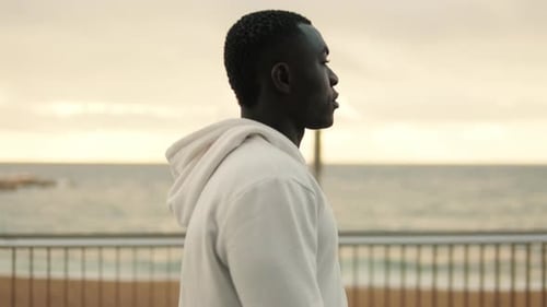 Handsome athlete man walking down the boardwalk, feeling tired after street workout