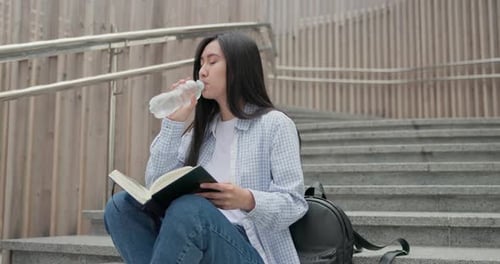 Woman Reading Book Outdoors on Concrete Steps