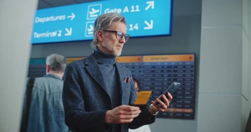 Airport Terminal Mature Man Scanning Plane Ticket Using Smartphone to Check Flight Information