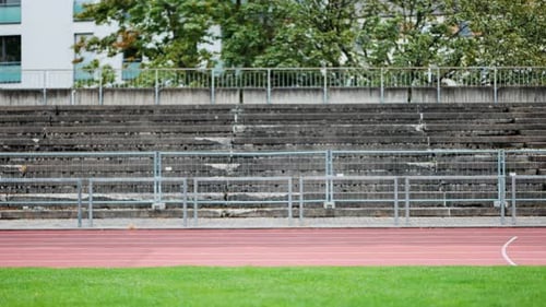 Two male runners pass camera on running track during training