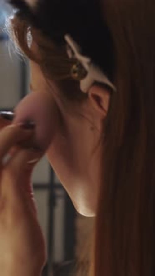 Young Woman Applying Makeup with Brush Indoors