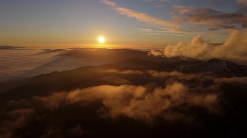 Sunset above a sea of fog and low clouds with mountain ridge aerial view of foggy mountains