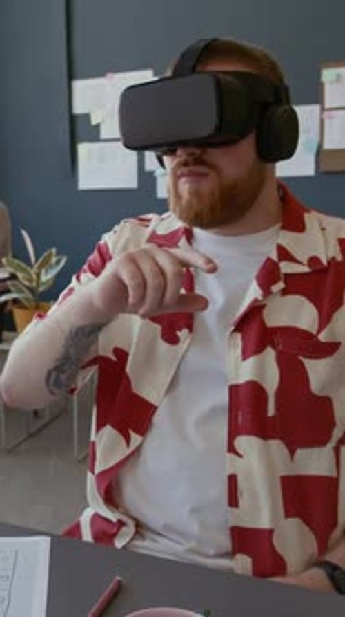 Vertical of Male UX Designer with VR Goggles Testing App at Office Desk