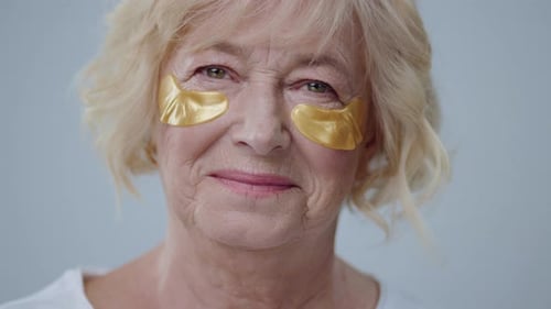 Senior Woman with Golden Eye Patches close-up portrait