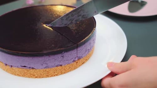 Knife Cuts Layered Purple Cake on Plate
