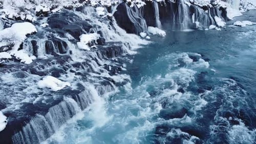 Waterfall in Iceland Frozen Snowy Mountain with Cold River in Winter Aerial