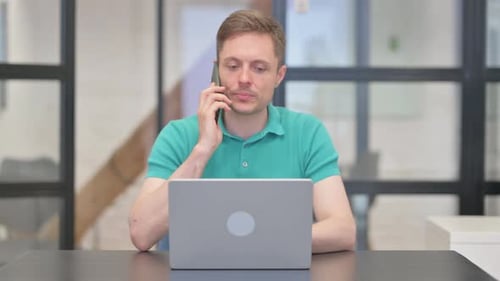 Young Adult Works, Answers Smartphone in Office