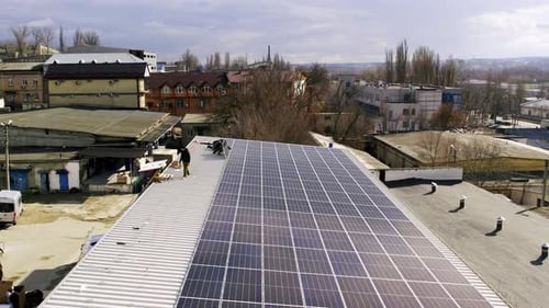 Workers Install Solar Panels on Building Rooftop