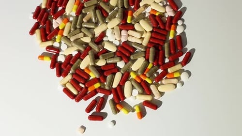 Colorful Capsules and Pills Scattered on White Surface