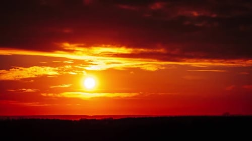 Zeitraffer eines Dramatisch Sonnenuntergangs durch Wolken am orangefarbenen Himmel über dem Horizont