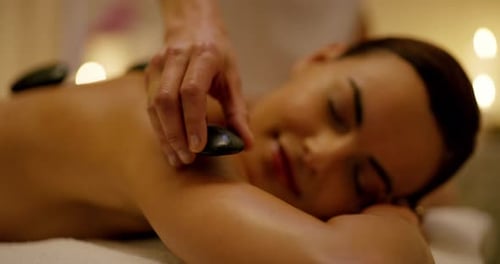 A young woman getting a hot stone treatment at a day spa