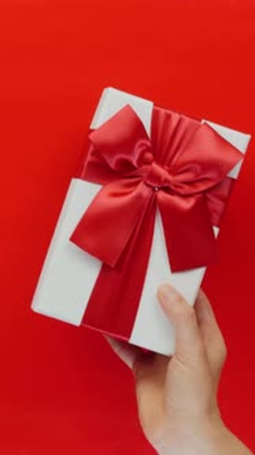 Hand Holding Birthday Gift with Red Ribbon
