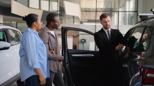 Couple Choosing New Car at Dealership with Salesman Assistance