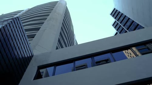 The low angle panning view of the city skyline buildings and blue sky.