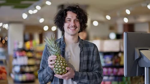Man Holds Pineapple in Grocery Store