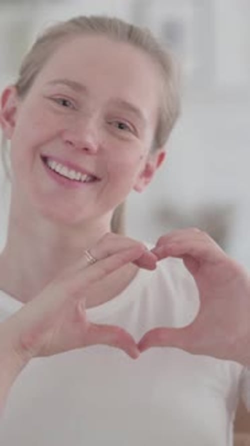 Smiling Woman Makes Heart Shape with Hands
