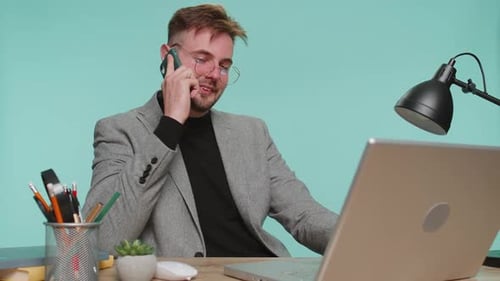 Happy Business Man Boss Enjoying Mobile Phone Call Talking with Colleague at Office Workspace Desk