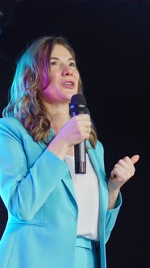Woman Giving Presentation on Stage with Microphone