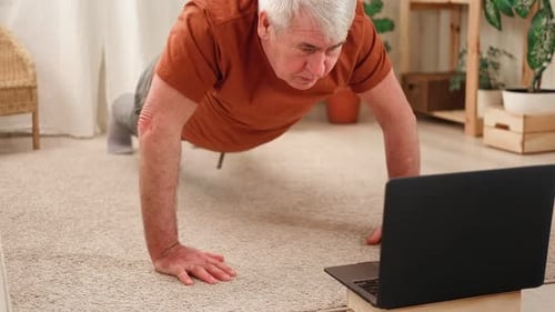 Hombre mayor maduro feliz haciendo ejercicios de gimnasia en casa en línea con una computadora portátil Estilo de vida saludable