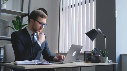 Young Adult Man Working on Laptop in Office