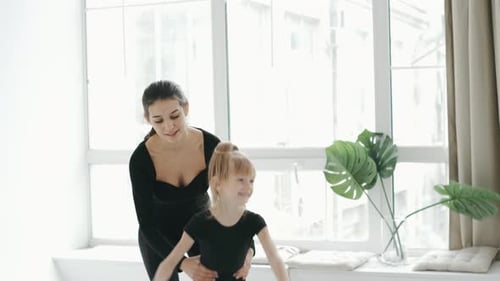 Entraîneur professionnel de Cherleading dansant avec une petite fille se déplaçant de façon synchronisée pendant un cours de danse