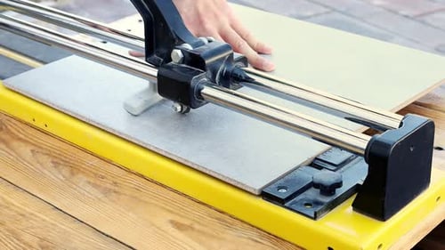 Construction worker cuts ceramic tile using tile cutting hand machine in slow motion