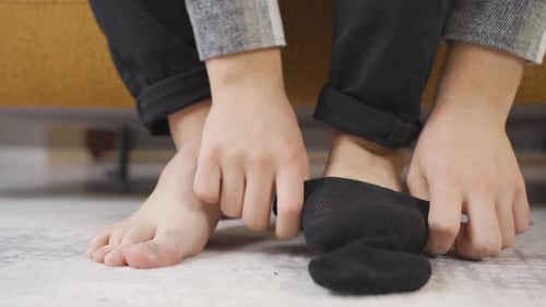 Adult Putting on Black Sock at Home