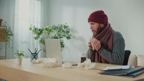 Sick Man Blowing His Nose While Suffering From the Flu Remote Working at Home