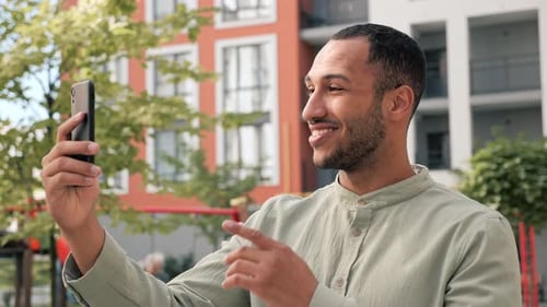 Man Using Phone for Video Call Outdoors