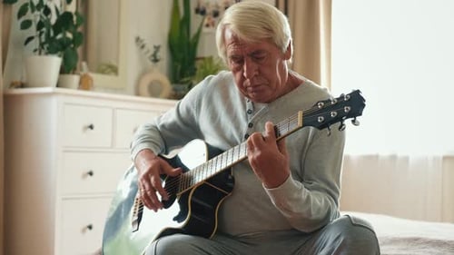 Senior Man Playing Guitar in Bright Room