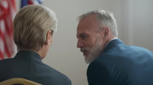 Two Adults Talking with National Flags in Background