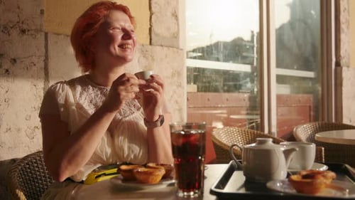 Woman drinks coffee in European cafe at sunrise