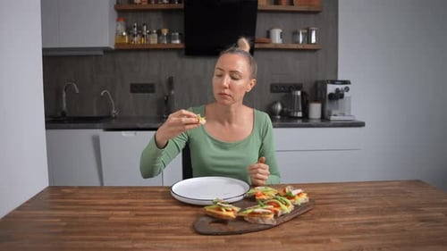 Woman Eats and Prepares Vegetable Sandwich in Kitchen