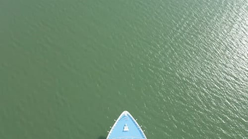 Luxury cruise ship making way ahead. Static top down aerial view of vessel passing below.