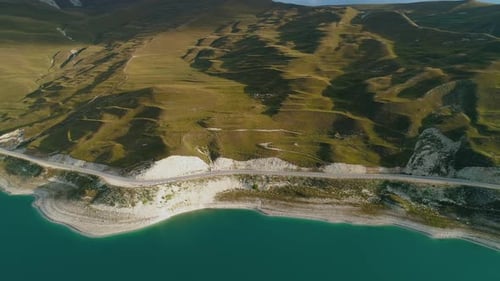 Aerial Over the Roadway Along Lake Kezenoyam with Turquoise Water and Tall Mountains Stunning
