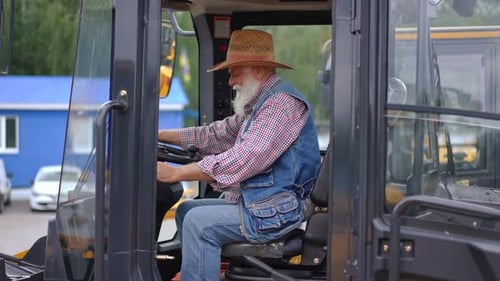 Wide Shot Side View of Happy Senior Farmer Sitting in Tractor Turning Looking at Camera Gesturing
