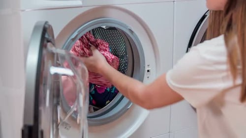 Woman Loading Clothes into Modern Washing Machine