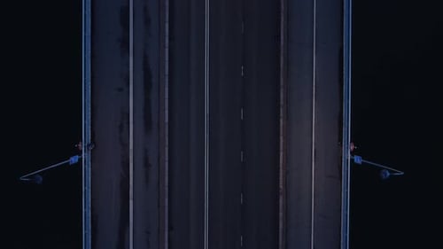Aerial looks directly down on to bridge deck traffic during blue hour