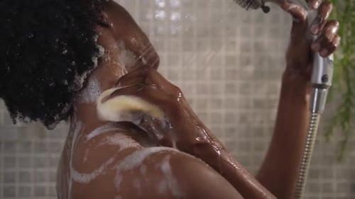 Woman Showering in Bathroom with Sponge and Showerhead