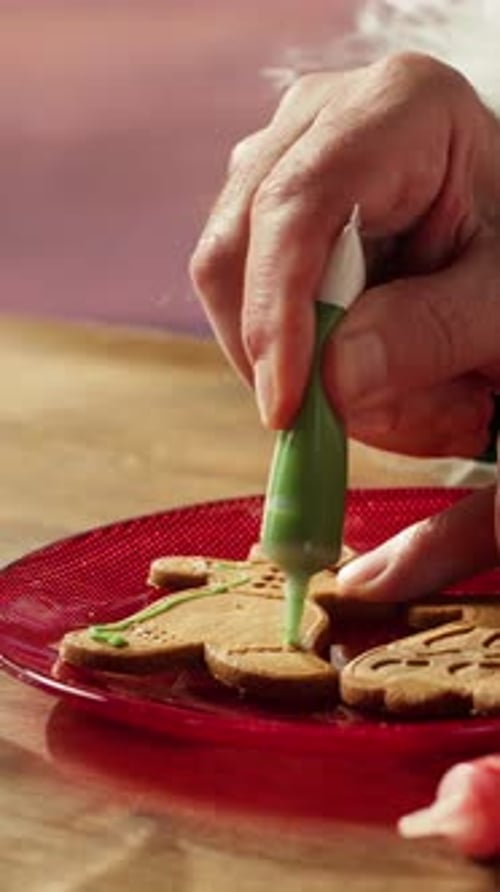 Vertical Video Santa Claus Decorates Gingerbread Cookies with Multicolored Icing