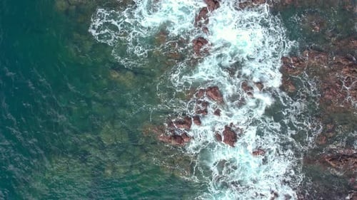Slow Motion Drone Orbit of Ocean Waves Crashing on Sharp Coastal Rocks