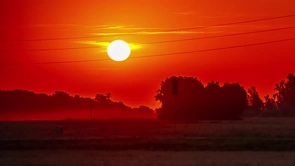 View of red sun rising in timelapse. Sun rising over a field during ...