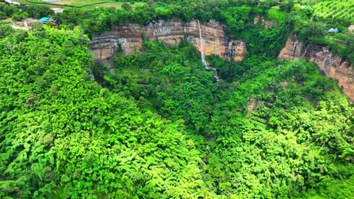 Drone soars above majestic waterfall on cliff.