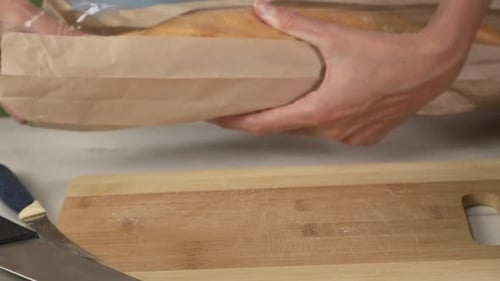 Baguette Being Pulled out of Paper Packaging