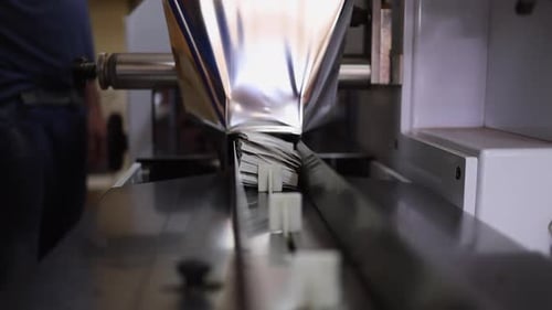 Tea bag stack on conveyor feeds into heat sealed foil packaging station